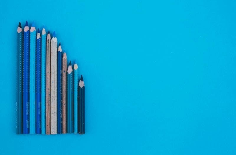 A mix of different sized pencils is laying on a blue surface