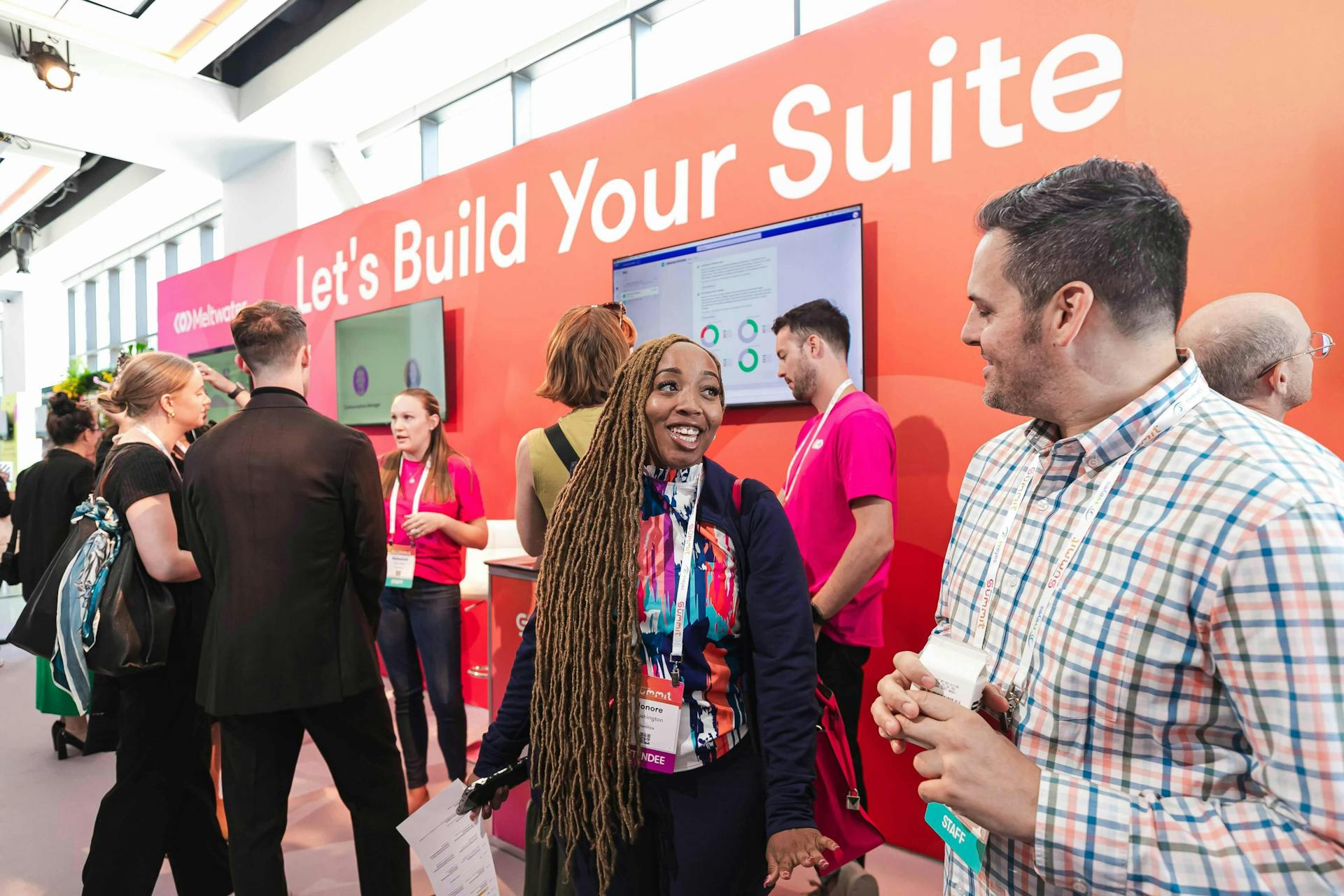 Image of smiling Meltwater Summit 2024 attendees gathered in front of the Product Demo Hub