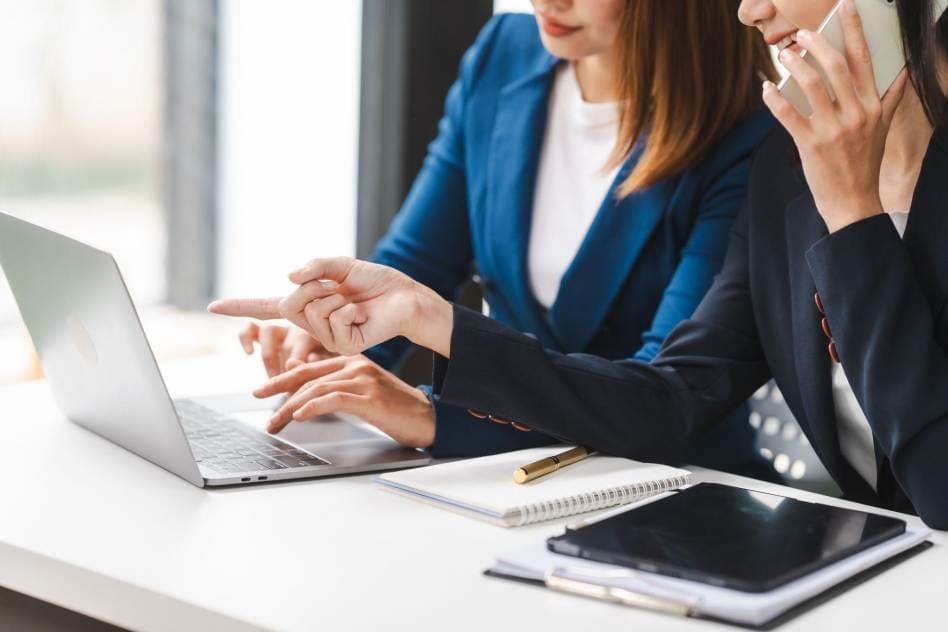 two female PR professionals working together on a laptop